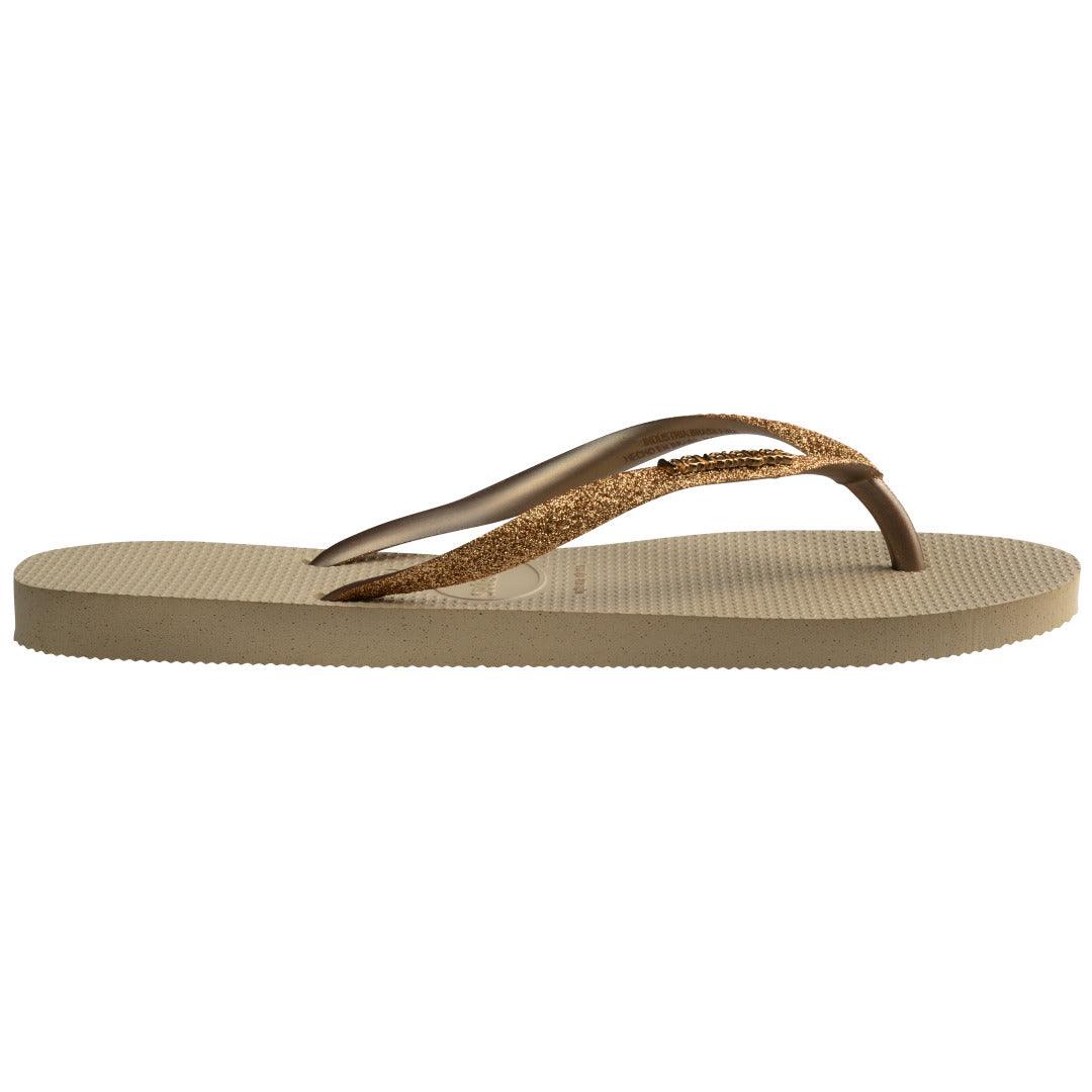 Chinelo Havaianas Slim Glitter II visto de perfil lateral mostrando o solado fino em borracha cor areia e tiras com glitter.